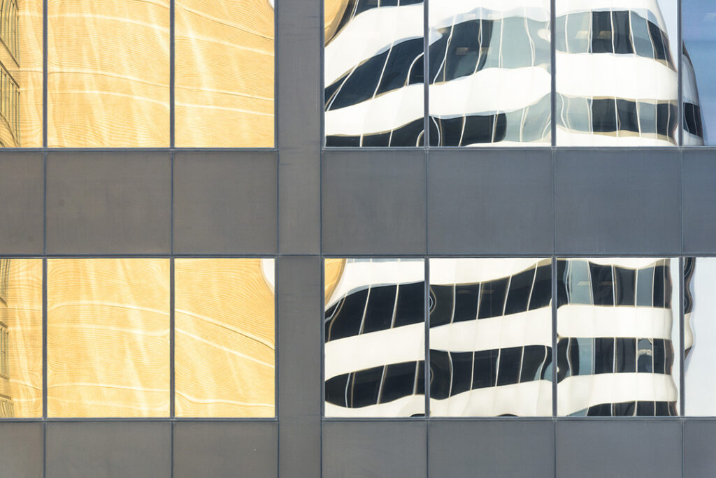 Close-up of hotel - grid-like pattern of gray panels and windows with reflections of nearby buildings